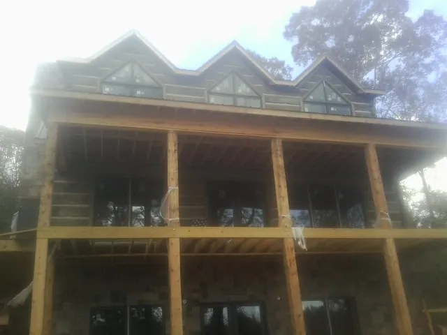 Dormers and porch framing on a large log home under construction — Roof Coating work by our crew in Coolin