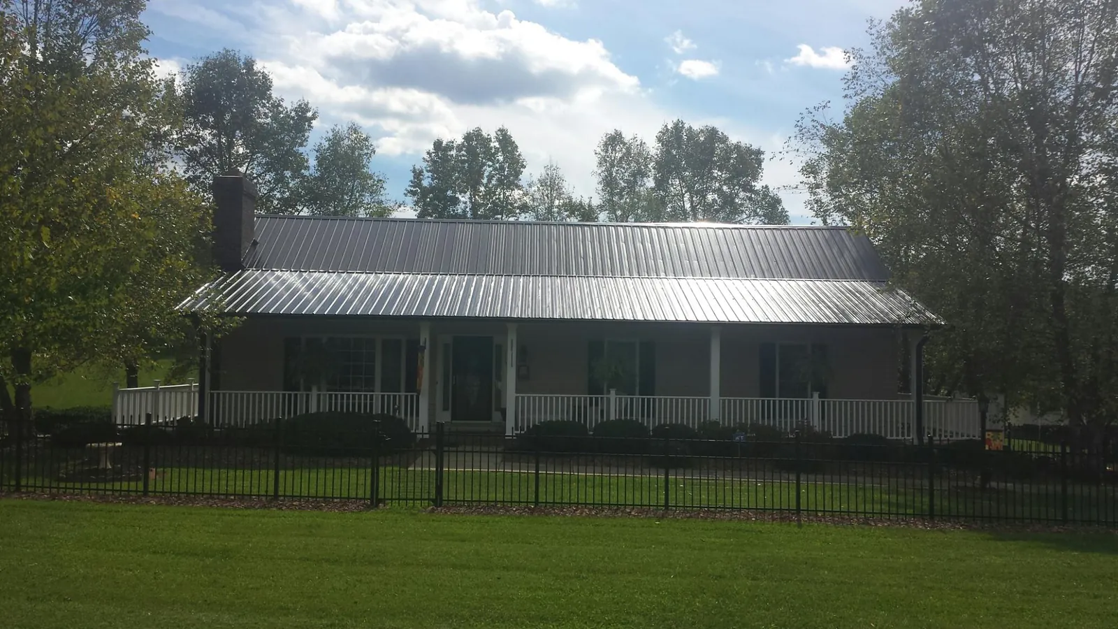 Gray metal roof on a brick ranch with a full width front porch — Gutter Guard Installation work by our crew in Coolin